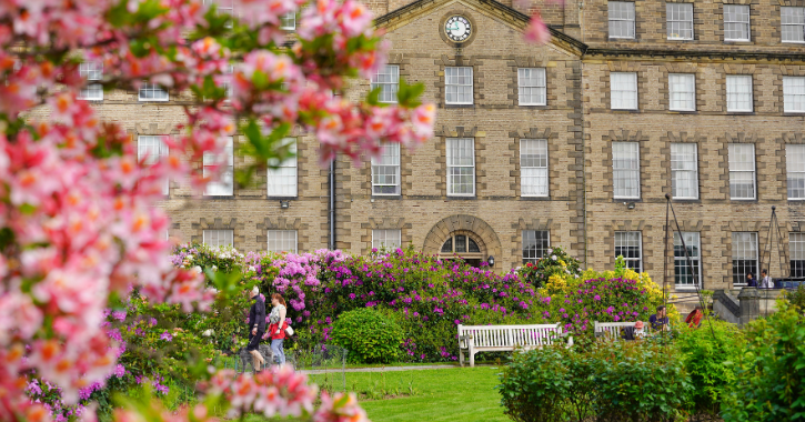 Two people walking through the gardens at Ushaw with bright colourful flowers filling the garden.